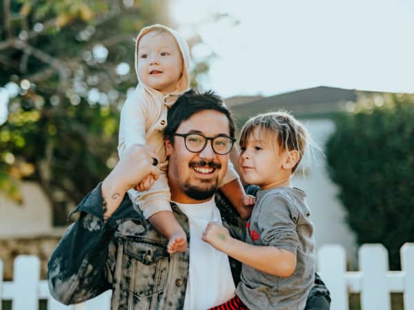Junger Vater mit seinen zwei Kindern auf dem Arm. 