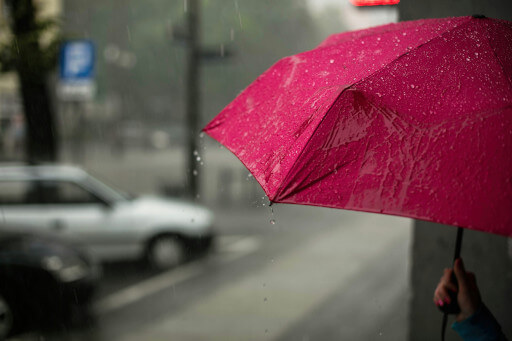Ein roter Regenschirm auf einer nassen Straße.