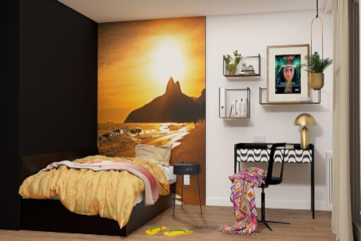 Mikroapartment mit Bett vor Fototapete, daneben eine Wand mit schönen Bildern. 
