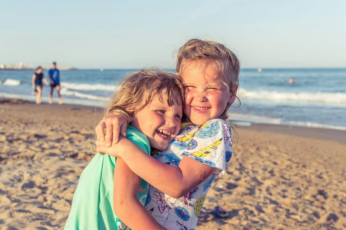 Zwei lachende Kinder am Strand.