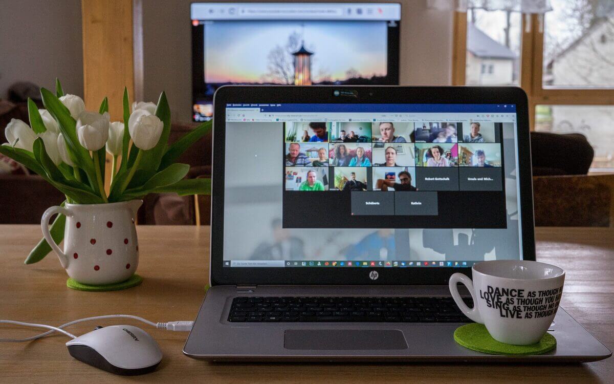HP-Laptop mit Videokonferenz-Bildschirm zeigt Teilnehmer in Kacheln.
