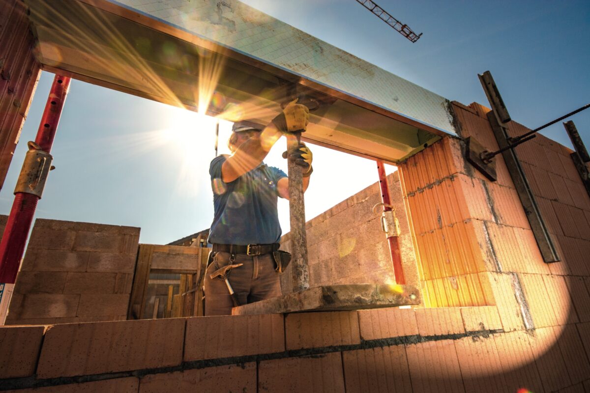 Bauarbeiter errichtet auf der Baustelle eine Gebäudestütze im Gegenlicht.